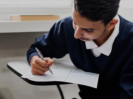 A student writing at a desk
